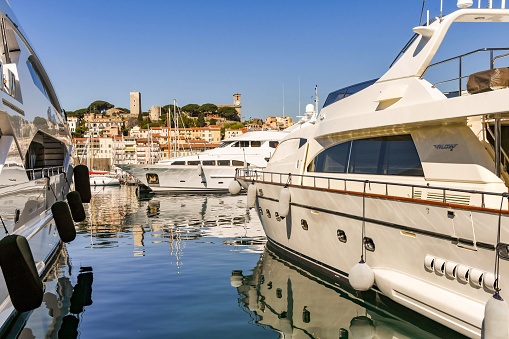 Cannes, France - April 2019: Super yachts moored in the harbour in Cannes. In the background is the castle and the Catholic church \