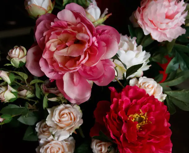 Photo of bouquet of artificial peonies on a dark background. Photo close-up