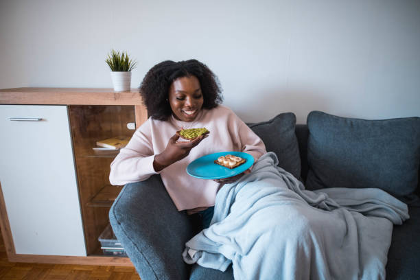 istock Young Black Woman Eating A Snack On The Sofa 1279207764