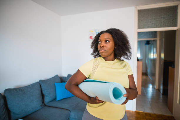 istock Black Young Woman Holding Exercise Mat And Looking Away 1279209303