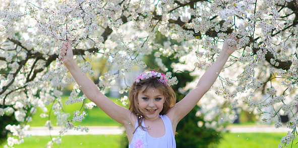 Pretty girl in blooming apple tree garden on beautiful spring day