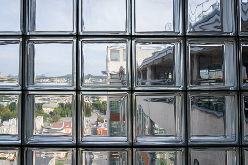 Distorted view of a town seen through glass blocks. Close up of glass wall allowing light to enter building interior.