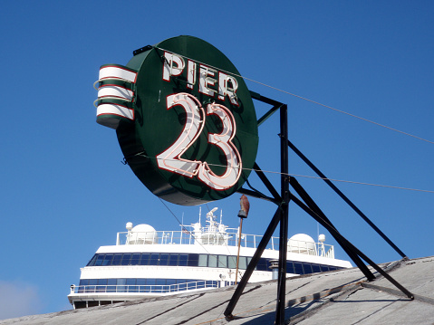 San Francisco - September 24, 2009: Pier 23 Cafe Restaurant and Bar Neon Sign on the roof with Cruise ship in the distance.