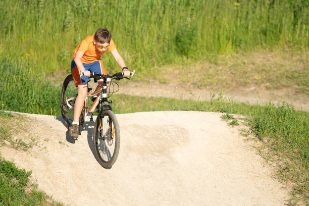 istock Boy in sunglasses riding a bicycle from a hillock 1279213933