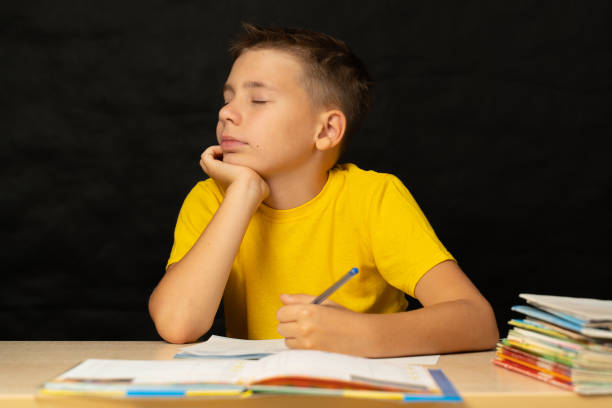 istock A boy dreams while sitting at a table, closing his eyes, doing homework 1279214442