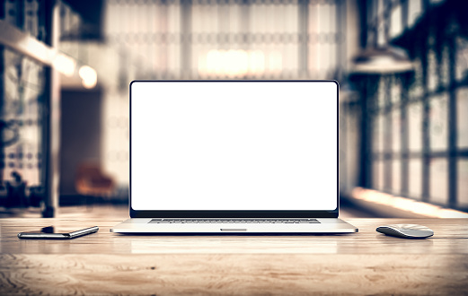 Laptop with frameless blank screen mockup template on table in industrial office loft interior - front view