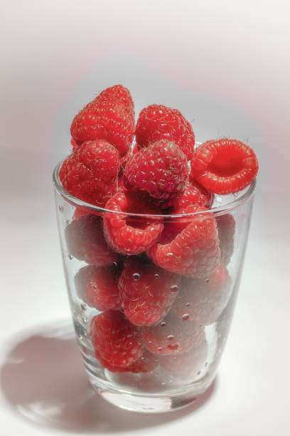 istock ripe raspberries in glass with shadows and grey background 1279217296