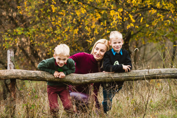 boys hang on wooden log with mother - twin falls imagens e fotografias de stock