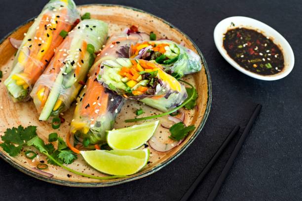istock Fresh Asian appetizer Spring rolls (Nem) made from rice paper and raw vegetables and herbs with hot sauce on a dark background. Vietnamese Food 1279220392