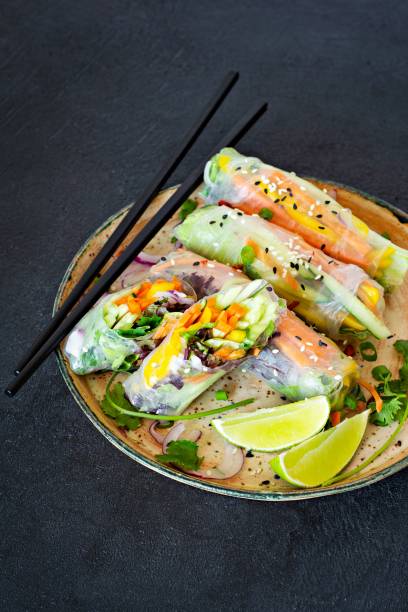 istock Fresh Asian appetizer Spring rolls (Nem) made from rice paper and raw vegetables and herbs with hot sauce on a dark background. Vietnamese Food 1279220394