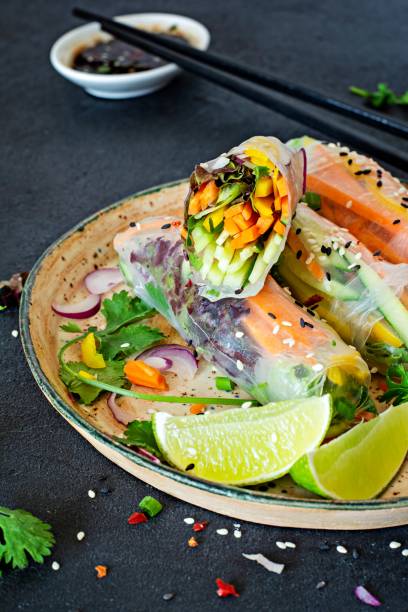 istock Fresh Asian appetizer Spring rolls (Nem) made from rice paper and raw vegetables and herbs with hot sauce on a dark background. Vietnamese Food 1279220402