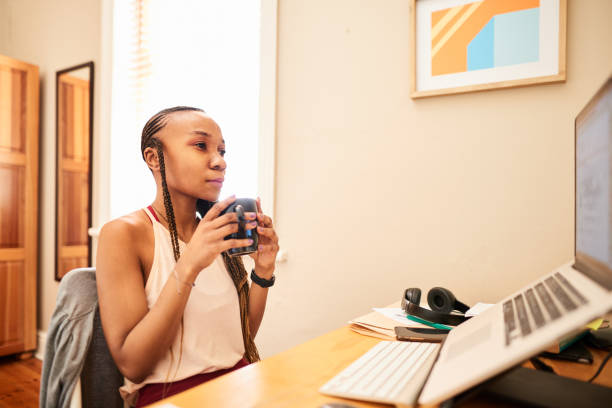 istock Young woman drinking a coffee while working remotely from home on a laptop 1279227575