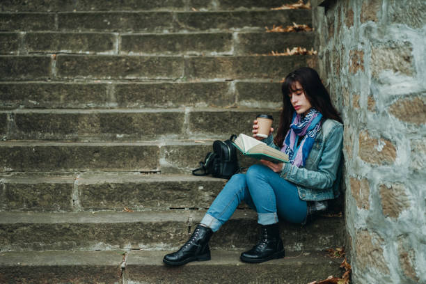 istock Young woman reading novel while sitting on steps 1279228560