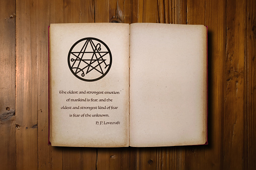 Close-up on an opened dark fantasy book with a the sigil of the Gateway with beneath, a quote from H. P. Lovecraft saying \