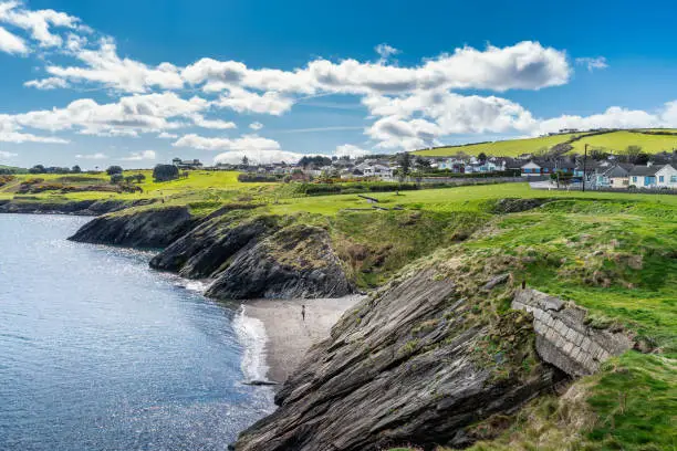 Photo of One woman standing on rocky beach between cliffs, Wicklow