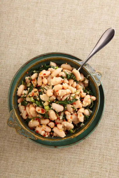 Delicious cannellini white bean salad in a colorful green dish with copy space seen overhead.