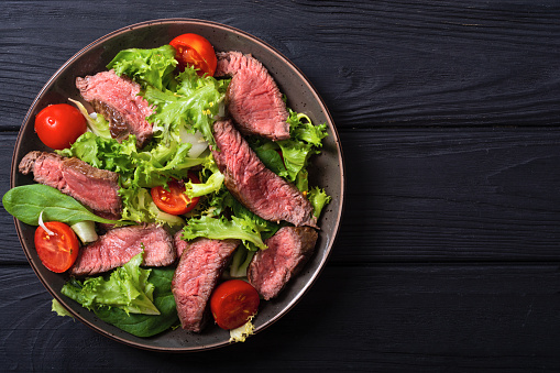 Salad with grilled beef medium roast . On wooden background