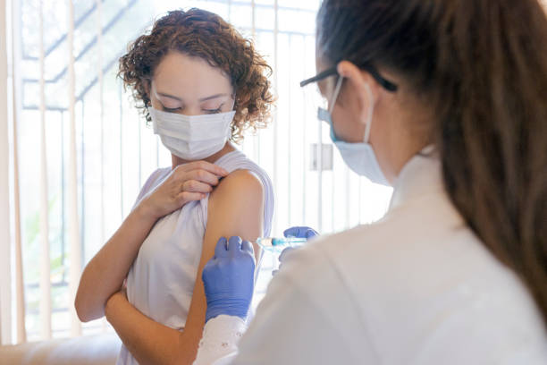 Nurse applying vaccine to patient at home stock photo
