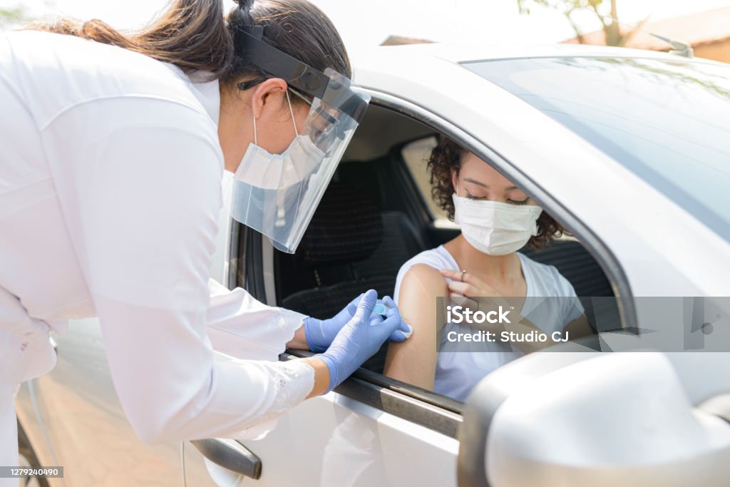 Nurse performing immunization in the car Nurse performing immunization in the car. Vaccine concept for covid-19. Vaccination Stock Photo