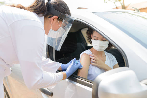 Nurse performing immunization in the car stock photo