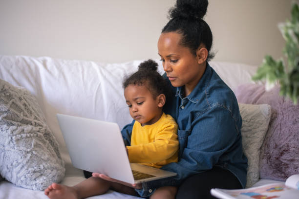 istock Young boy sits in her mom's lap and helps work on the computer 1279240611