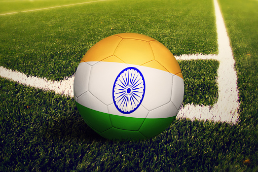 India flag on ball at corner kick position, soccer field background. National football theme on green grass.