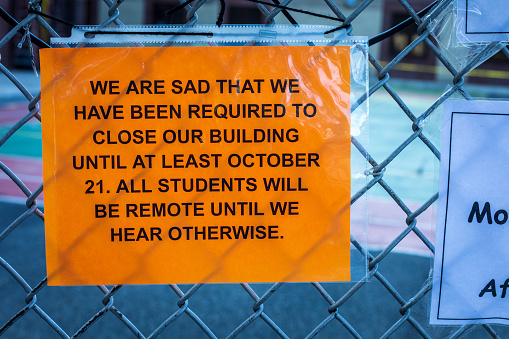 Sign posted on school fence announcing school closure due to COVID-19. Brooklyn, NY. USA