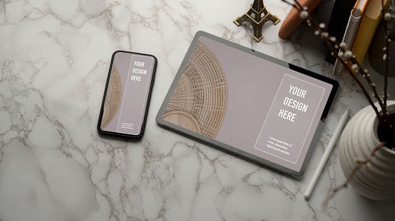 Top view of marble worktable with mock up tablet, smartphone, books and copy space