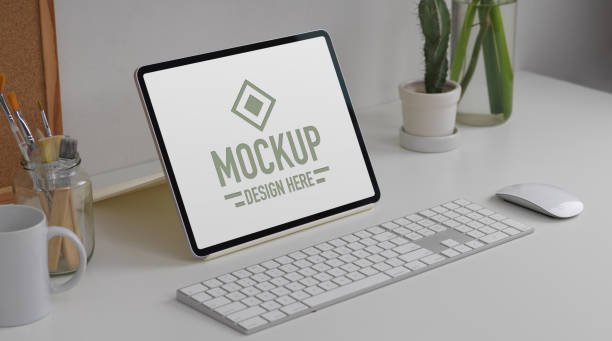 Worktable with mock up tablet, keyboard, mouse, stationery and plant vase on white table