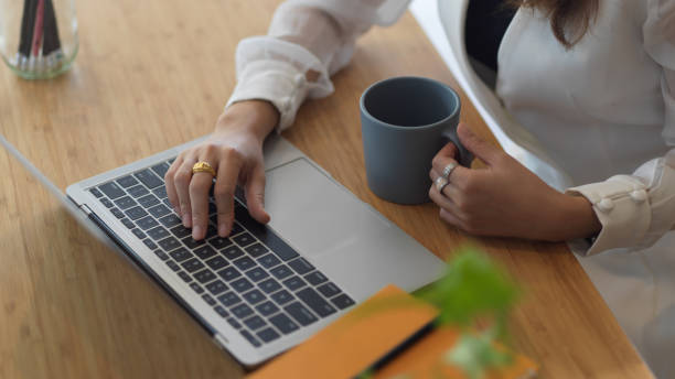 istock Female working with laptop and holding coffee cup on wooden table 1279254334