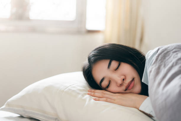 jeune femme asiatique adulte dorment dans la chambre à coucher le matin - pillow hotel bed sleeping photos et images de collection