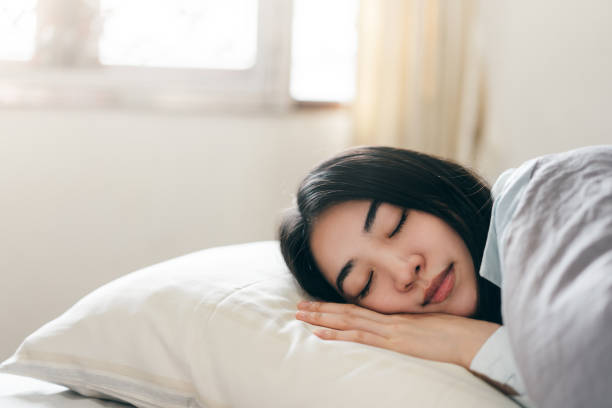 giovane donna asiatica adulta dormire in camera da letto la mattina - sleeping women bed pillow foto e immagini stock