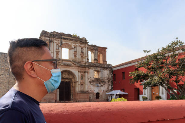 homem da guatemala de antígua andando com uma máscara facial na frente de ruínas antigas - guatemala antigua central america color image - fotografias e filmes do acervo