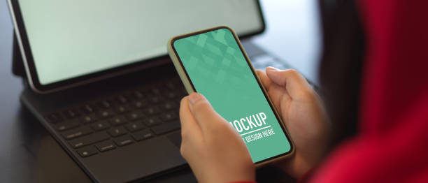 istock Female hands holding mock up smartphone while working with mock up tablet 1279261287