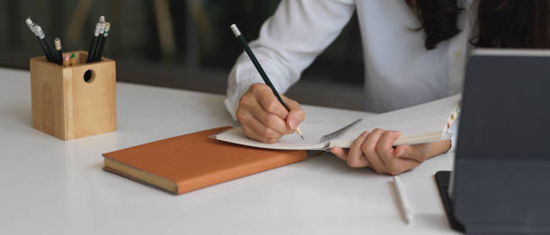 istock Female hand writing on schedule book on office desk 1279263588