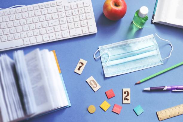 istock Distance learning during the coronavirus epidemic. Open book, computer keyboard, disposable face shield and sanitizer gel disinfectant. Workplace at school photo top view 1279263616