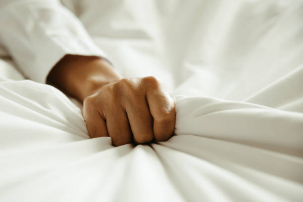 close up hand of female pulling white sheets in ecstasy , feeling and emotion concept - passion sexual activity sexual issues sex imagens e fotografias de stock