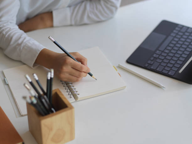 istock Female hand writing on blank notebook with pencil on office desk 1279264395
