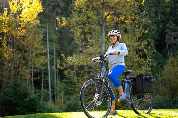 Senior woman riding an e-bike Active senior woman. Senior enjoying the great outdoors. Woman riding an e-bike electric bicycle photos stock pictures, royalty-free photos & images