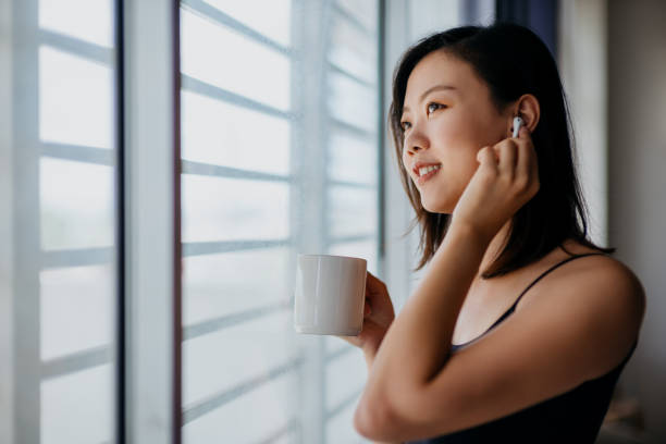 jeune femme asiatique retenant la tasse de café et regardant par la fenêtre - the thinker audio photos et images de collection