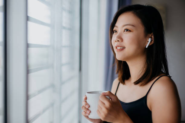 jeune femme asiatique retenant la tasse de café et regardant par la fenêtre - the thinker audio photos et images de collection