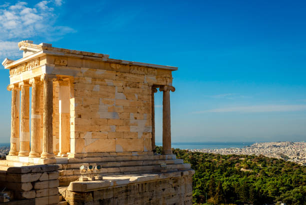 храм афины найк, на акрополе афин, греция, названный в честь греческой богини афины. филопаппос хилл, пирей и саронический залив находятся н� - nike стоковые фото и изображения