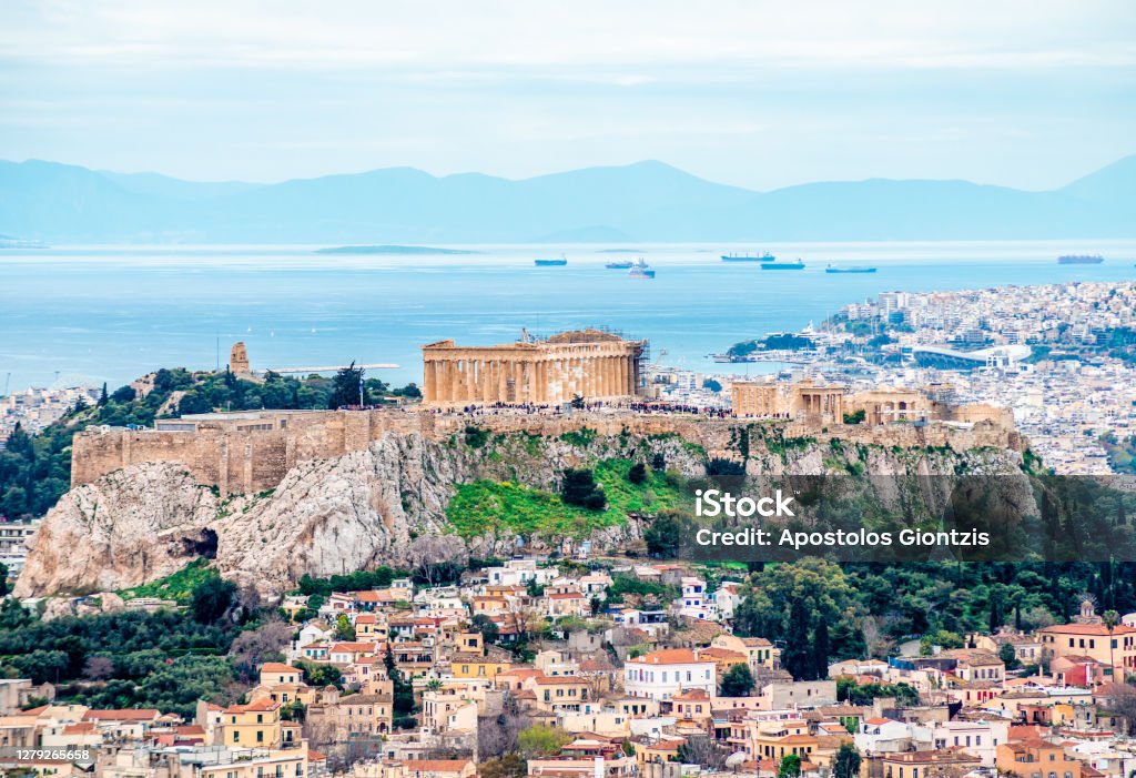 The Acropolis of Athens with Filopappos or Philopappou Hill and the Saronic Gulf. View of the Acropolis of Athens, Greece, with Filopappos Hill, the Saronic Gulf and the port of Piraeus in the background. Picture taken from Mount Lycabettus. Bay of Water Stock Photo