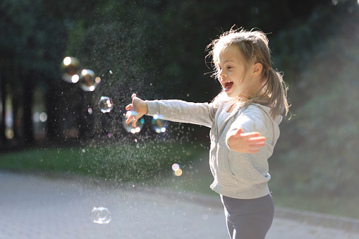 Little girl Having fun with the soap bubbles outdoors