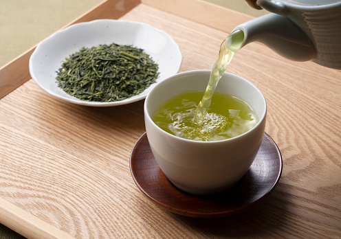 Pouring green tea into a teacup. Japanese green tea image