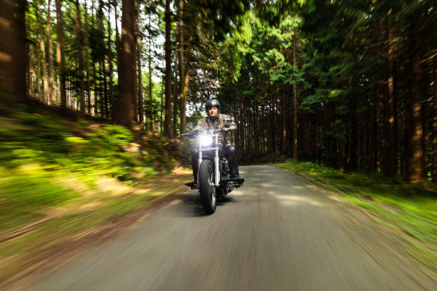 September/29/2020 at Gozaisho mountain forest road a man is riding his Harley Davidson motorbike. The trees and road have motion blur due to the slow shutter speed used.