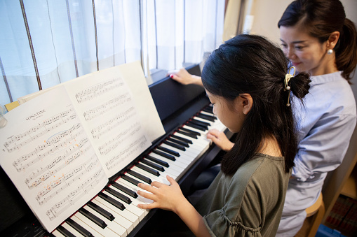 Daughter taking piano lessons with her mother
