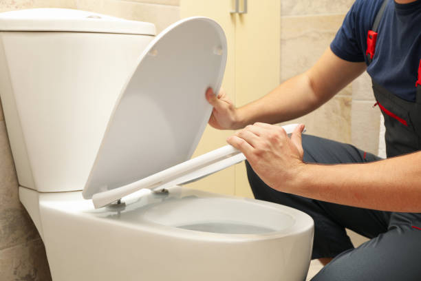 istock The plumber in overalls fixes the toilet 1279273749