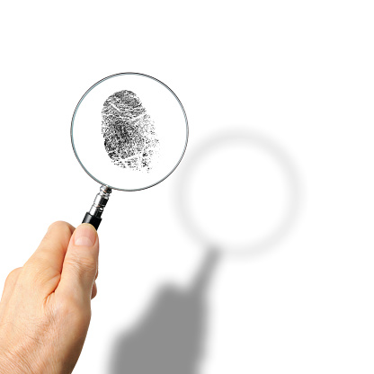 Holding a magnifying glass to see fingerprints, isolated on white with shadow.