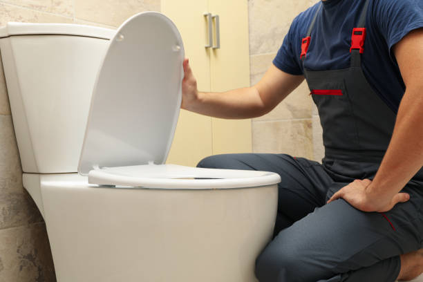 istock The plumber in overalls fixes the toilet 1279274675